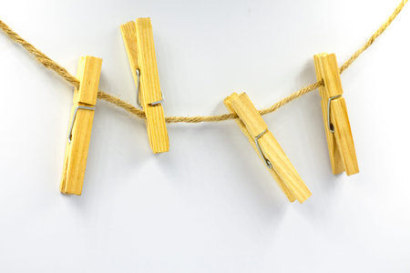 Wooden clothespins hanging on a natural hemp rope isolated on white background.