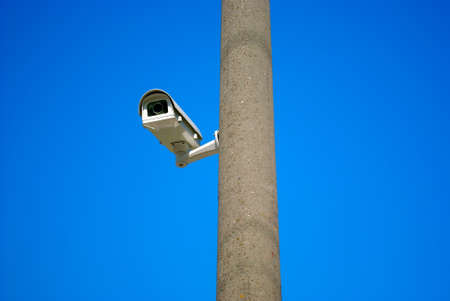 surveillance camera on the gray column on the background of blue skyの写真素材