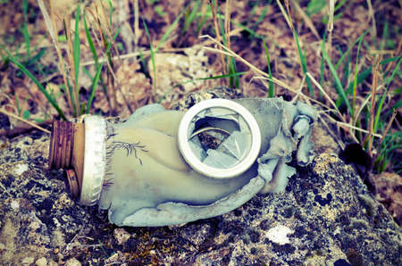 Vintage, broken gas mask lying on a rock on a background of grassの写真素材