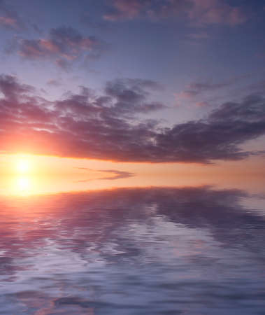 Dramatic sunset in the sky with bright sun and clouds over the ocean. Natural sunrise composition