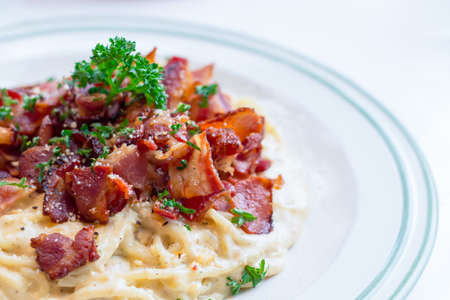Dish of Italian spaghetti carbonara sauce with bacon and cheese on white table.の写真素材