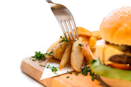 Roasted rosemary garlic potato fries with home made hamburger, beef, lettuce, cheese, tomato and potato fries on wooden tray.の写真素材