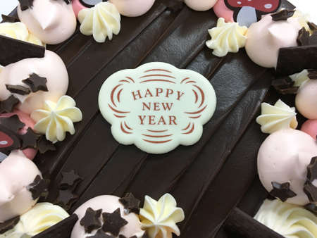 Tasty chocolate cake with chocolate ship, cream topping, white chocolate cake decoration, Happy New Year.の写真素材