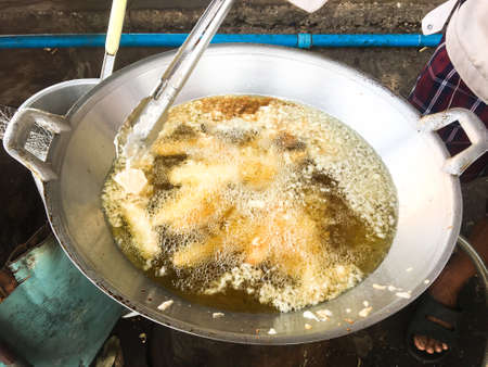 Banana chips of fried in hot coconut oil on iron pan, Food in Thailand.
