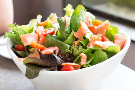 Fresh leaf vegetable salad with smoked salmon and tomato on table.の写真素材