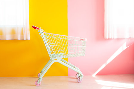 Online shopping concept pastel color trolley on yellow and pink background texture. Fashion style. Copy space for text. Fashion style.の写真素材