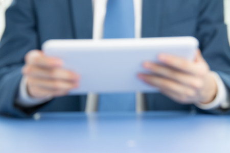 businessman touch tablet to businessman in blur backgroundの写真素材