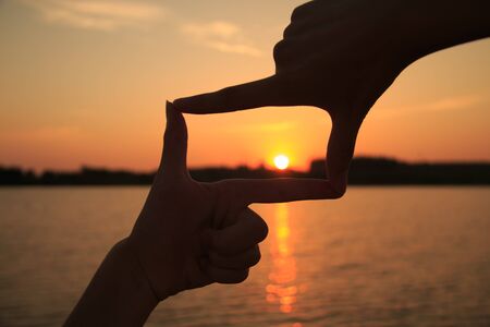 Hand frame against the sunsetの写真素材