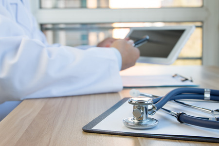 Close-up of stethoscope and folder on background of doctors at workの写真素材