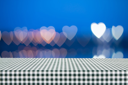 Empty table covered with green tablecloth over light bokeh background