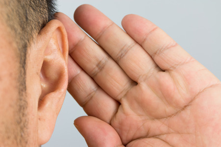 man holds his hand near his ear and listeningの写真素材