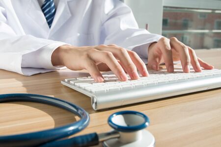 Close up of doctor's hand at computer typingの写真素材
