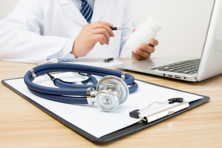 Close-up of stethoscope and folder on background of doctors at workの写真素材