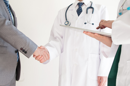 Doctor and businessman shaking handsの写真素材