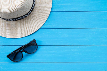 Straw hat and sunglasses on woodの写真素材