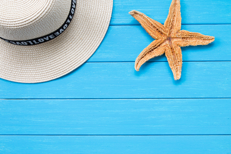 Straw hat and starfish on woodの写真素材