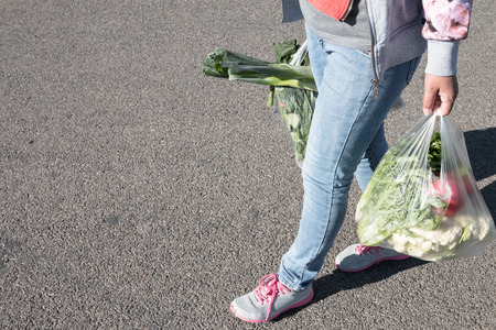 Woman holding a plastic bag of vegetables