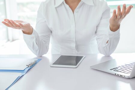 Midsection of businesswoman seated on desk with hand gesture