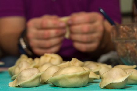 Dumplings hand-made on the background of handsの写真素材
