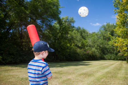 Youth hits wiffle ball in green fieldの写真素材