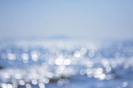 blurred sunlight reflected in the blue sea waves at daytimeの写真素材