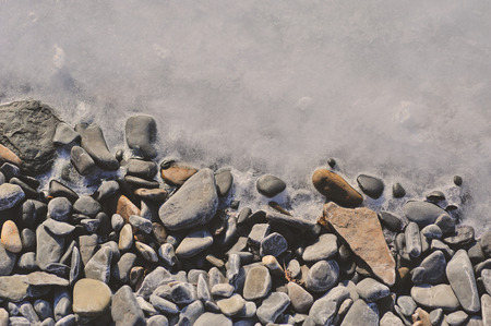 pebble on the beach frozen into waterの写真素材