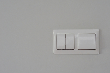White plastic double switch on grey painted interior wall