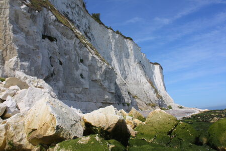 White cliff against a blue sky with rocks in the foreground の写真素材