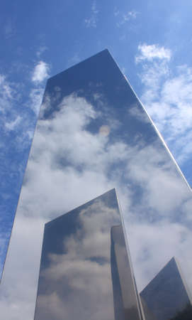 A metal object reflecting a blue sky with white clouds