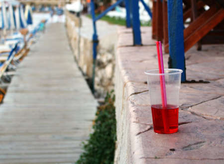 Cold red drink with straw at the beachの写真素材