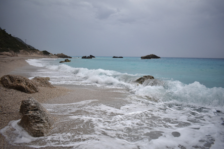 blue sea, waves and sand, and cloudy skiesの写真素材