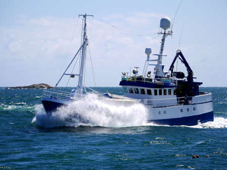 Fishing boat underway at speed breaking wave.