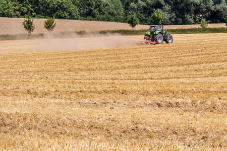 Tractor harvester working in wheat field in summer time