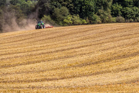 Tractor harvester working in wheat field in summer timeの写真素材