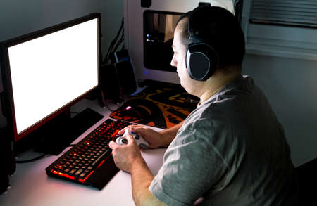 Man playing computer game on custom made desktop with joypad, keyboard, mouse.の写真素材