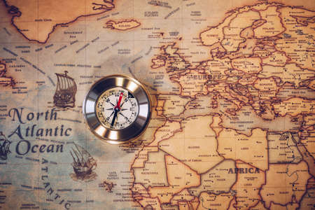 Old vintage retro golden compass on ancient map. Selective focus, shallow depth of field. Concept of world travel, sightseeing and tourism.の写真素材