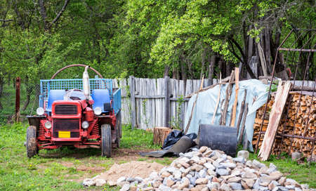 Rural scene of a backyard with tractor and wood pileの写真素材