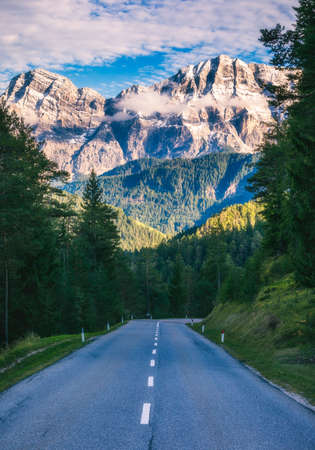 Dolomite Alps in Italy. Beautiful day. The road passes in the coniferous forests at the foot of limestone and dolomite rocks. The concept of active and car tourismの写真素材
