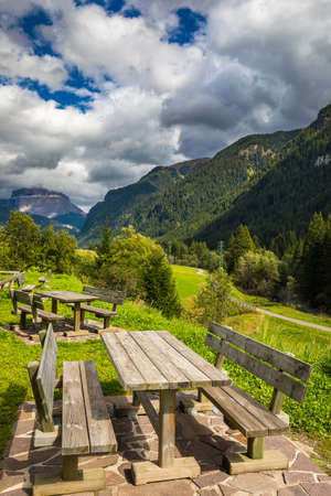 Nature landscape. Amazing view on Alps, valley and mountains at summer. It's time for lunch in the mountains. Picnic table in Dolomites mountains, wooden bench in the mountain valley.の写真素材