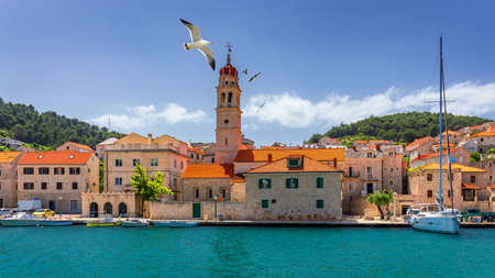 Panorama of picturesque town Pucisca in Croatia, Island Brac, Europe. Pucisca town mediterranean panorama with seagull's flying over the town. Croatia, Island Brac, Europe.の写真素材