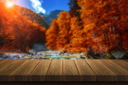 Empty wooden table for product placement or montage with focus to table top in the foreground. Mock up for display of product. Beautiful background with forest, waterfall, incredible landscape.の写真素材