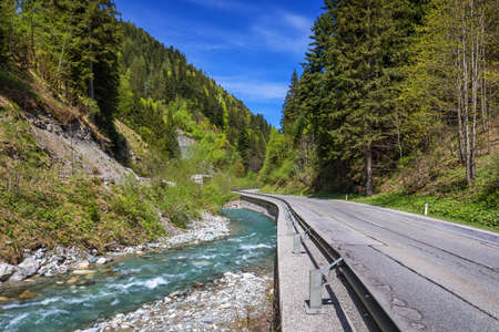 Asphalt road in Austria through the forest, valley in Austria in a beautiful summer day. Alps mountains tranquil summer view (Austria)の写真素材