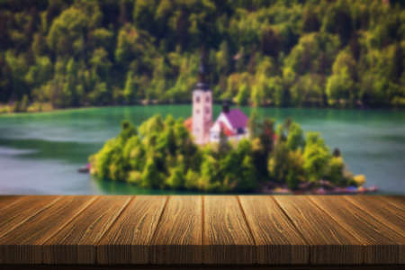 Empty wooden table in front of abstract blurred background in nature, can be used for display or montage your products. Mock up for display of product. Bled island in the background from Slovenia.の写真素材