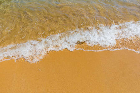 Soft wave of blue ocean on sandy tropical beach. Background of tropical paradise beach with golden...