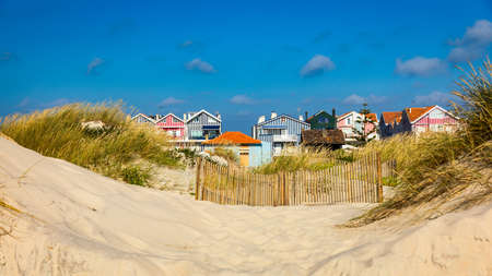 Idyllic and quaint beach houses seen from beach dunes. Beach houses with colorful stripes from Costa...
