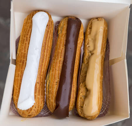 Colorful Eclairs In The Box. Eclairs Laying Inside White Boxes. Eclair Cakes With Scalded Carmel And...