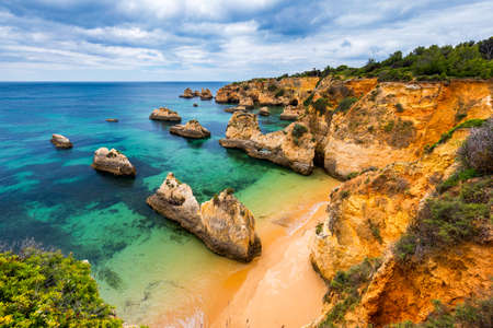 View of stunning beach with golden color rocks in Alvor town , Algarve, Portugal. View of cliff rocks on Alvor beach, Algarve region, Portugal.の写真素材