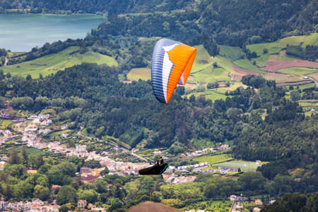 Paragliding in paradise landscape with volcano crater and lagoon in Azores. Paraglider above Lagoa das Furnas, Sao Miguel, Azores, Portugal, Europeの写真素材