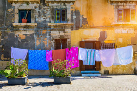 Siracusa (Syracuse) in a sunny summer day. Sicily, Italy. The clothes being dried in the narrow street of the famous historic town Syracuse, Sicily.の写真素材