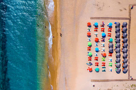View from above, stunning aerial view of an amazing beach with beach umbrellas and turquoise clear water. Top view on sun loungers under umbrellas on the sandy beach. Concept of summer vacation.の写真素材